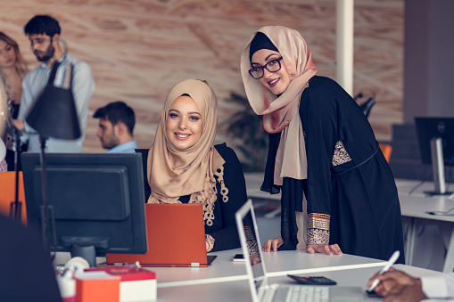 Two woman with hijab working on laptop in office